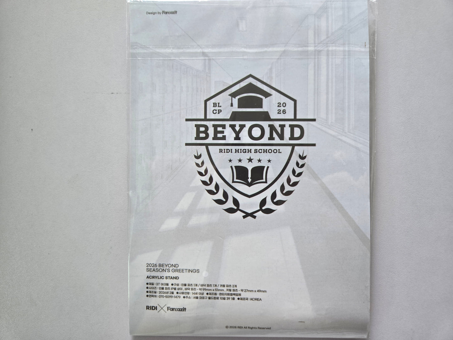 A clear plastic stand sleeve containing a white printed display stand with a black graphic logo that reads '2026 BEYOND' season greetings and 'RIDI HIGH SCHOOL'.