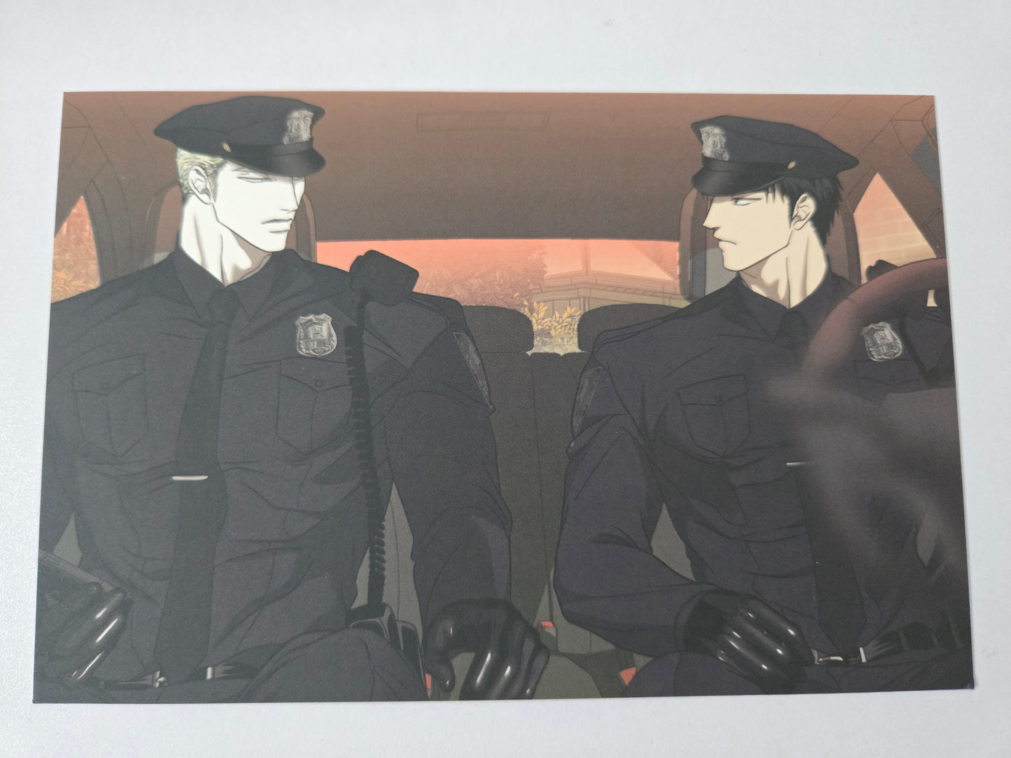 Postcard showing Jake and Shin in uniforms seated inside a car