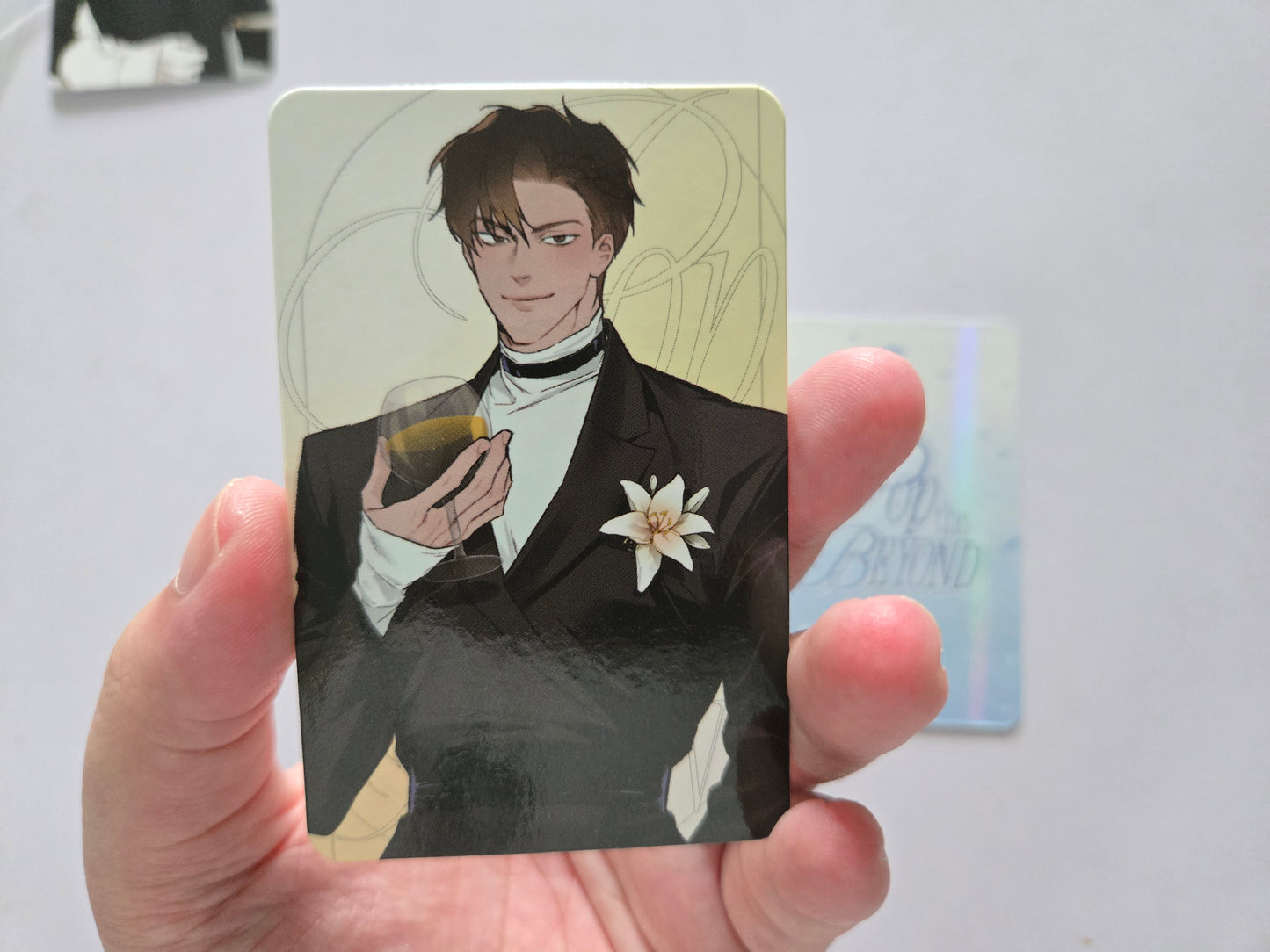 Taekjoo in a black tuxedo holding a glass, with a white flower on the chest. 