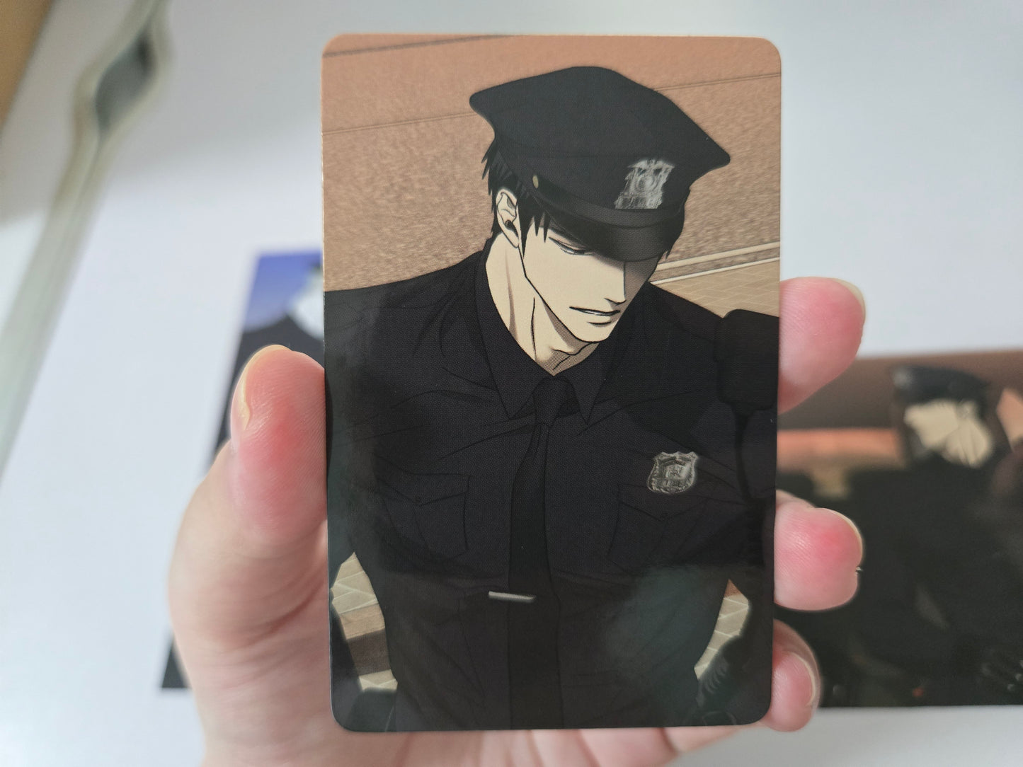 Rectangular printed card featuring Shutline Shin in police uniform and cap with orange background.