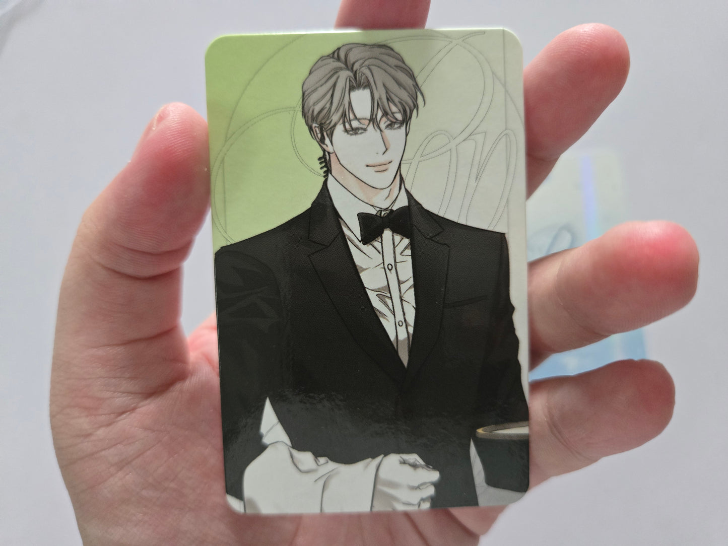 Woo-won photocard in a black tuxedo with a white shirt and black bow tie, against a pale green background.