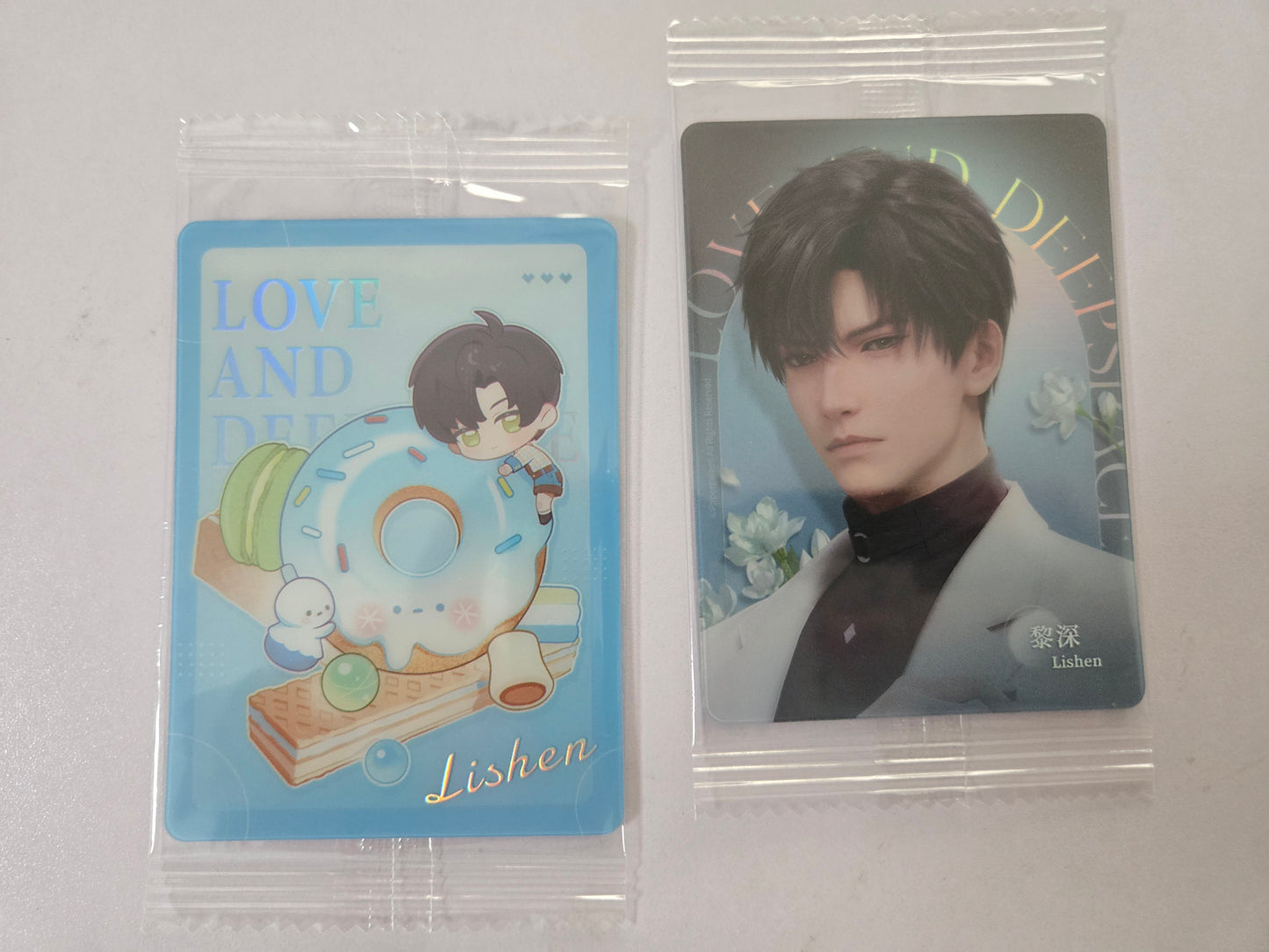 Zayne collectible cards. 
a blue illustrated card with Zayne and the name 'Lishen' on the left, and a portrait card of a man in a white suit on the right.